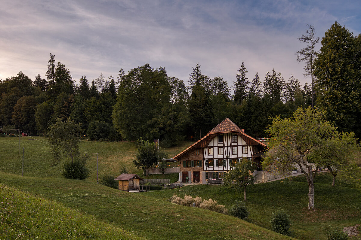 Historisches Fachwerkhaus des L&ouml;chlibad am Waldrand im Emmental bei Abendd&auml;mmerung